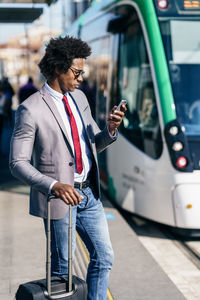 Man holding mobile phone while standing in city