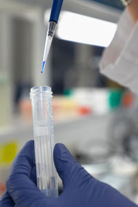 The lab technician performs the experiment by injecting the blue liquid into a test tube