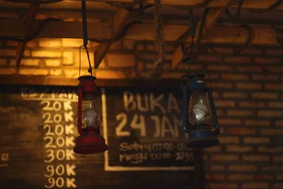 Low angle view of illuminated light bulb hanging on wall