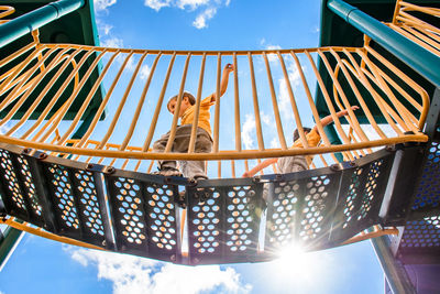 Two boys running across bridge at playground on a sunny day