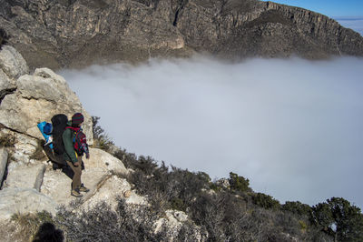 Woman standing on rock against cloudscape