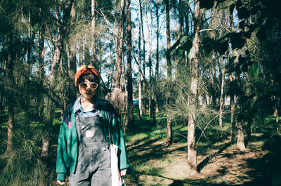 Portrait of woman standing against trees in forest