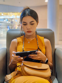 Young woman using mobile phone while sitting in gym