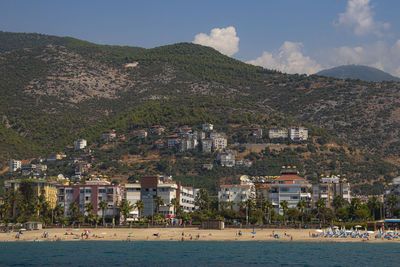 Scenic view of beach by town against sky