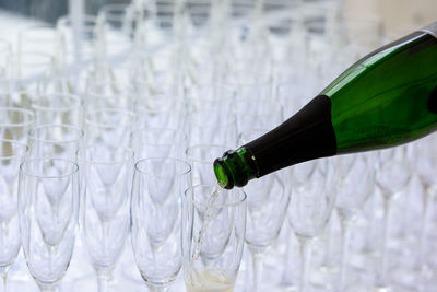 Closeup of a champagne bottle pooring champagne into a champagne flute against a blurred glasses 