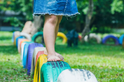 Low section of girl walking on tires in playground