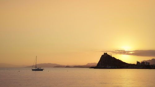 Sailboats in sea at sunset