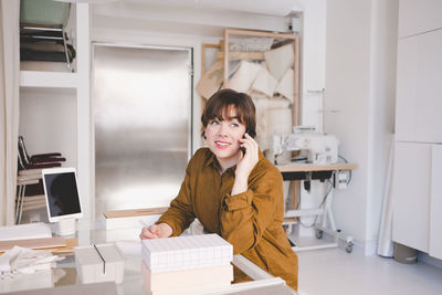 Smiling upholstery worker looking away while using mobile phone in store