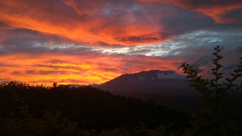 Scenic view of silhouette mountains against orange sky