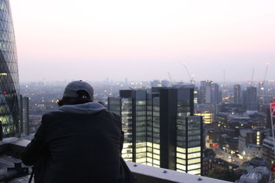 Rear view of man and cityscape against sky