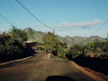 Road by trees against sky