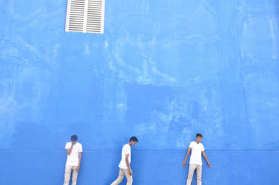People standing against blue wall