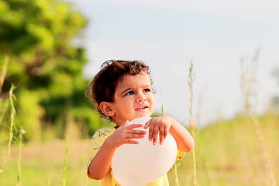 Portrait of cute girl holding plant on field