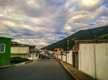 Road by houses against sky