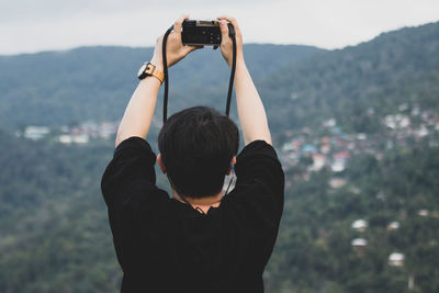 Rear view of man photographing at camera