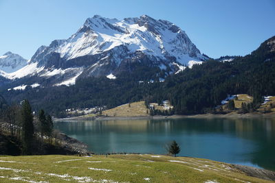 Scenic view of lake by snowcapped mountains against sky