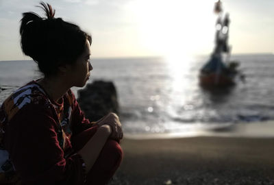 Side view of woman on beach against sky during sunrise