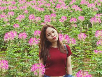 Beautiful young woman standing by pink flowers