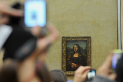 Crowd photographing mona lisa picture frame on wall