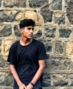 Thoughtful young man standing against wall