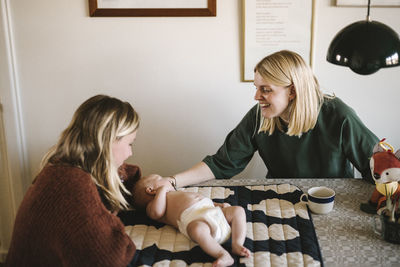 Smiling mothers relaxing at home with newborn baby