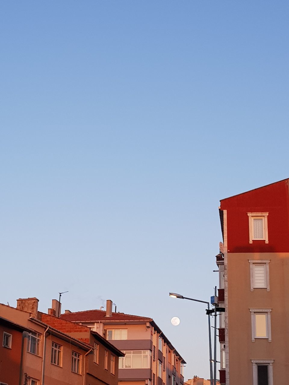 architecture, building exterior, built structure, building, sky, copy space, clear sky, nature, residential district, blue, low angle view, no people, house, day, city, high section, outdoors, red, antenna - aerial, communication, electric lamp, row house