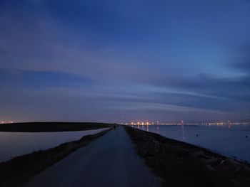 Road by sea against sky at sunset