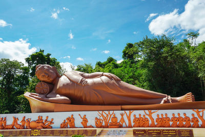 Low angle view of buddha statue against trees