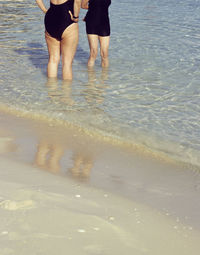 Low section of man standing on wet beach