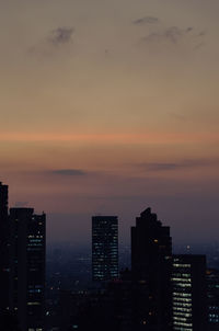 Illuminated buildings against sky at sunset