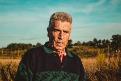 Portrait of man standing on field against sky