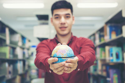 Young man holding globe in library