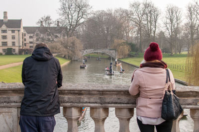 Rear view of man and woman standing against bare trees