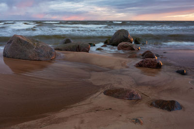 Rocks on shore at beach against sky