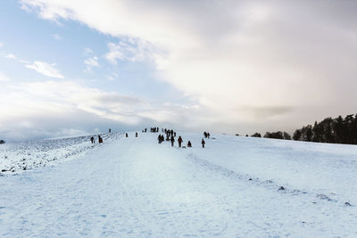 People on snow against sky during winter