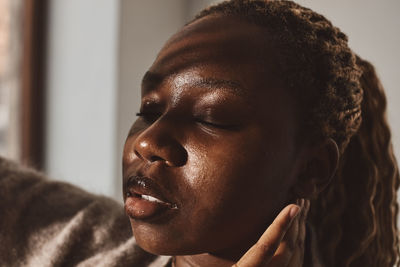 Young woman with eyes closed touching ear against wall