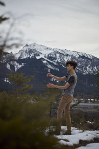 Full length of woman standing on snowcapped mountain against sky