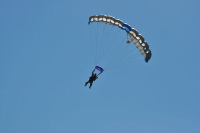 Low angle view of man paragliding against clear blue sky