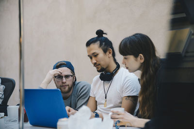 Computer programmers using laptop at desk in office