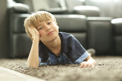 Portrait of boy lying down on rug at home