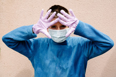 Portrait of man covering face against wall