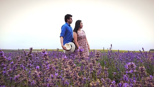 Full length of young woman with flowers on field