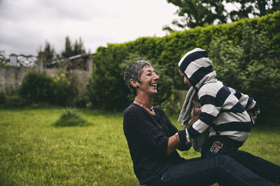 Happy grandmother with grandson on grassy field