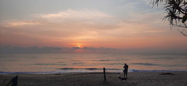 Man looking at sea against sky during sunset