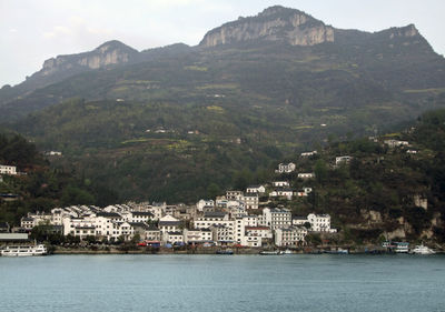 Scenic view of sea by buildings against mountains