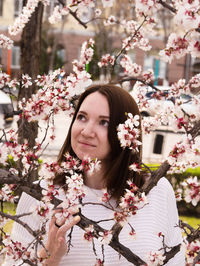 Beautiful young woman looking away by cherry tree