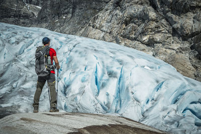 Rear view of man standing on snow covered mountain