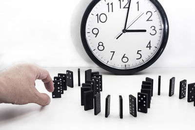 Close-up of hand holding clock against white background