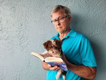 Senior man reading a book to his cute puppy.