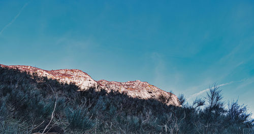 Low angle view of mountain against blue sky